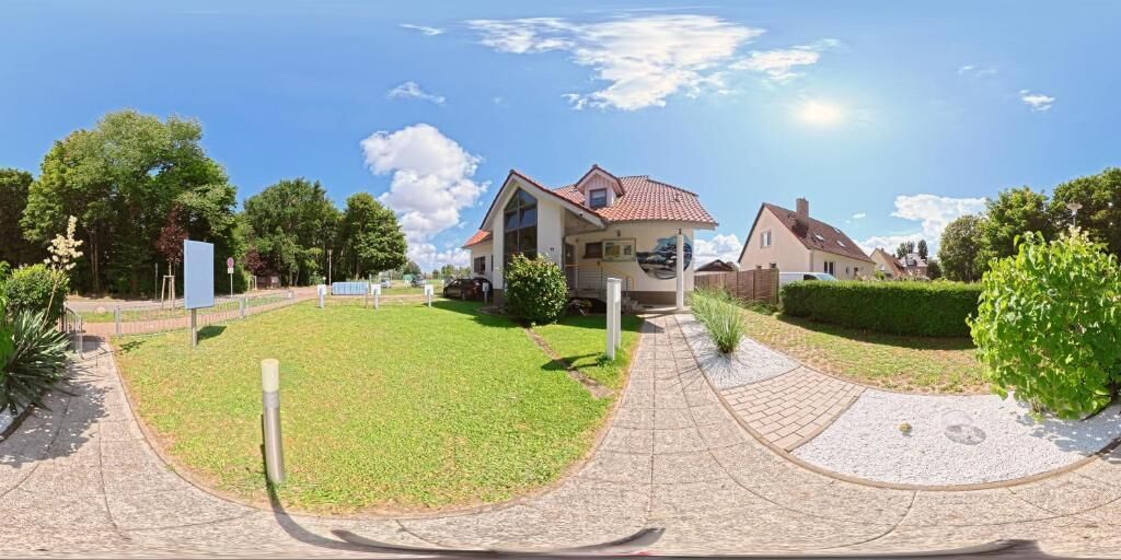 A residential area with a house, a paved driveway, and a well-maintained lawn.