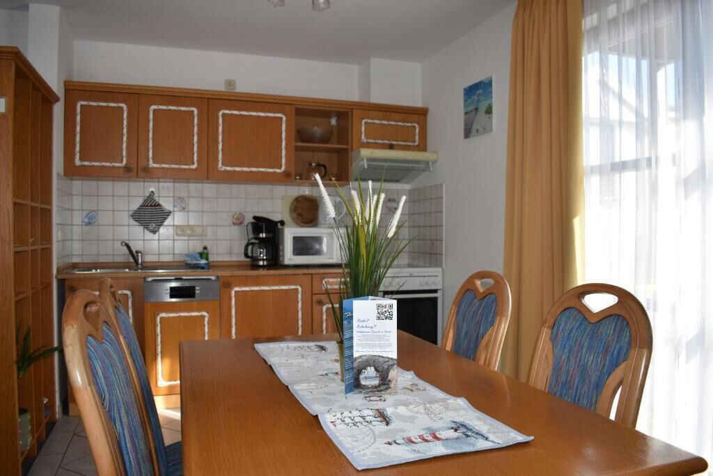 A kitchen with wooden cabinets, a microwave, and a dining table with chairs.