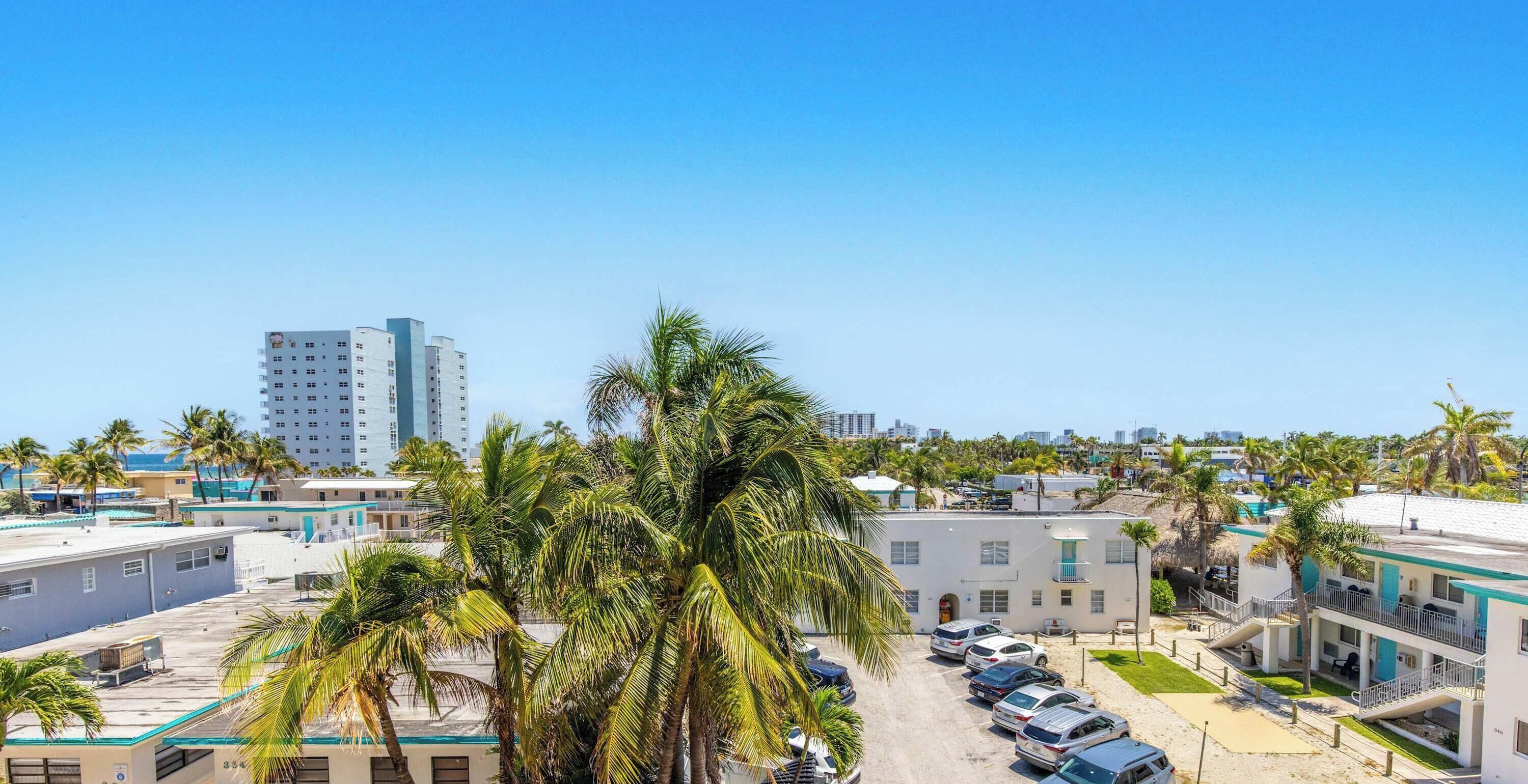 Un hôtel situé sur la côte, composé de plusieurs bâtiments à étages, doté d’un parking et agrémenté de palmiers.