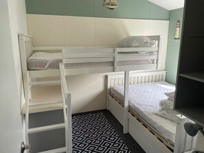 Ein Schlafraum mit Etagenbett, einer gemusterten Teppich und einem an der Wand befestigten Regal.
