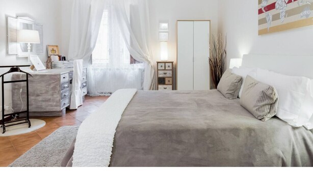 Een slaapkamer met een bed, nachtkastjes, een dressoir, een spiegel, een kledingkast en een muur met een kaart.
