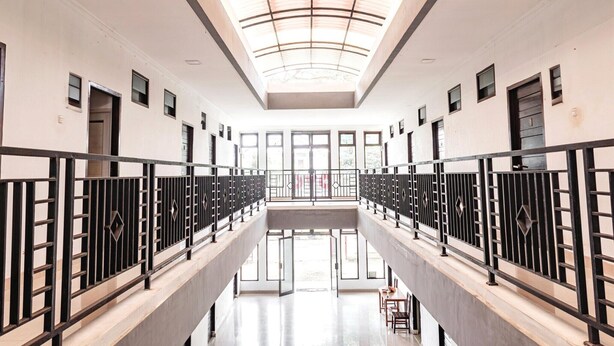 A modern interior with a central open space, railings, and a skylight.