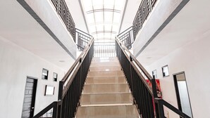A modern interior with a central staircase flanked by glass railings, leading to a high ceiling with a skylight.