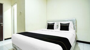 A neatly made bed with a white and black bedspread, a plain wall, and a door to the left. - Cozy Double Escape W/ Free WiFi and Parking (Palembang)