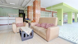 Un vestíbulo con un sofá, sillones, una mesita y un televisor.