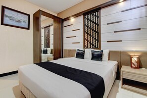 A hotel room with a large bed, a wooden headboard, a nightstand, a mirror, and a wall-mounted light fixture. - Luxury Deluxe DBL Retreat W/ Free WiFi and Parking (Solo)