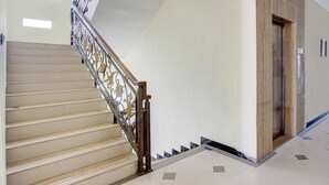 Una escalera con barandillas de metal ornamentadas, una puerta de madera y un suelo de baldosas.