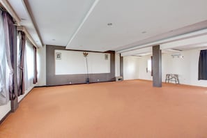 Tilava huone, jossa on suuri näyttö, projektori ja puinen tikapuut.