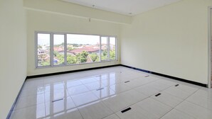 Una habitación amplia con un ventanal grande, piso de baldosas y una puerta.
