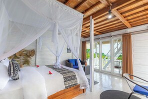 Ein Zimmer mit Bett, Stuhl und Blick ins Freie.