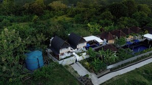 An aerial view of a resort with multiple bungalow-style buildings, a swimming pool, and lush greenery surrounding the property. - Nusa Sunshine Private Villa Ceningan (Ceningan Island)