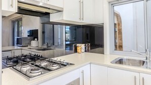 Una cocina moderna con armarios blancos, electrodomésticos de acero inoxidable, un ventanal y vistas al exterior.