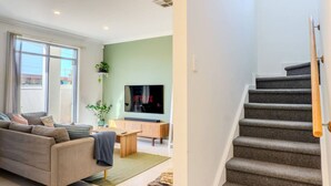 Una sala de estar moderna con sofá, televisor y escalera.