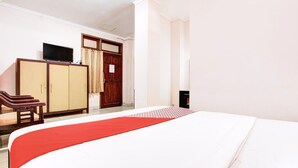 Habitación de hotel con cama, televisión sobre un mueble, armario y puerta con cortinas.