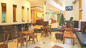 Eine Hotelhalle mit Empfangsschalter, Sitzgelegenheiten und einem Weihnachtsbaum.