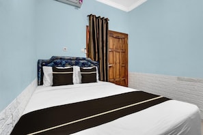 Une chambre à coucher avec un lit, une porte en bois et un mur en briques blanches.
