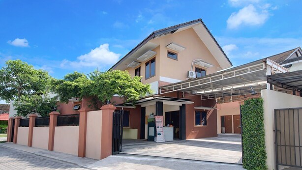 A modern building with a covered entrance, a gated driveway, and a small kiosk. - Cozy Double Escape W/ Free WiFi and Parking (Yogyakarta)