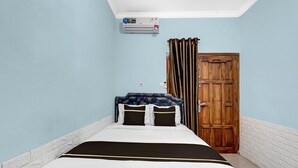 A single bed with a white and black bedspread, a wooden door, and a blue wall. - Cozy Double Escape W/ Free WiFi and Parking (Yogyakarta)