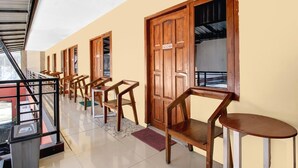 A corridor with wooden doors, a staircase, and a seating area with chairs and a table. - Cozy Double Escape W/ Free WiFi and Parking (Yogyakarta)