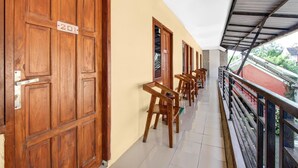 A corridor with wooden doors, a tiled floor, and a balcony with a metal railing. - Cozy Double Escape W/ Free WiFi and Parking (Yogyakarta)