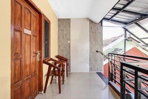 Un balcon avec une porte en bois portant l’inscription « 206 », une rambarde en métal et une vue sur la façade de l’immeuble.