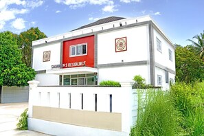 Un edificio de dos pisos con fachada roja y blanca, un letrero que dice 'SULAIN'S RESIDENCE' y una entrada con portones.