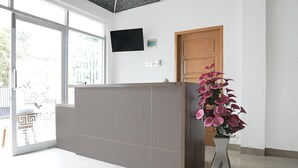 A reception desk with a large window, a flat-screen TV, and a wooden door. - Luxury Deluxe DBL Retreat W/ Free WiFi and Parking (Padang)