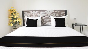 A neatly made bed with a black and white bedspread, a decorative headboard, and a small bedside table with a lamp. - Luxury Deluxe DBL Retreat W/ Free WiFi and Parking (Padang)