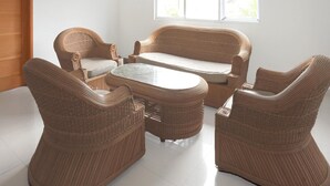 A wicker furniture set with a sofa and chairs, a small table, and a window providing natural light. - Luxury Deluxe DBL Retreat W/ Free WiFi and Parking (Padang)