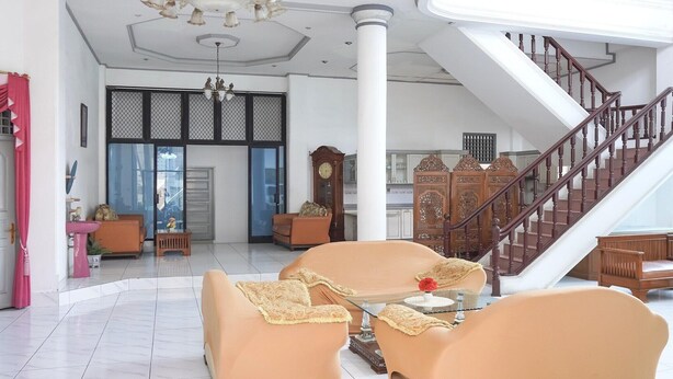 Un amplio salón con escalera, una araña y un ventanal grande.