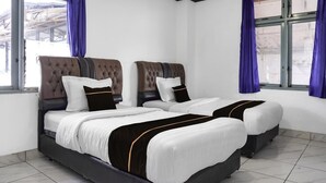 Quarto de hotel com duas camas, uma janela grande e vista para o exterior.