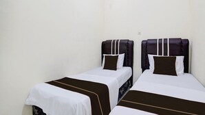 Ein Zimmer mit zwei Einzelbetten, jeweils mit Kopfteil und Kissen.
