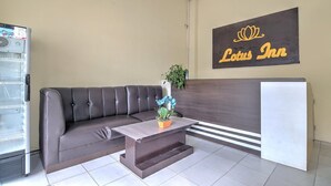 A reception area with a dark-colored sofa, a small table with a plant, a refrigerator, and a wall sign reading 'Lotus Inn'. - Stylish DBL Suite Escape W/ Free WiFi and Parking (Pekanbaru)