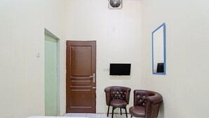 Ein Zimmer mit zwei Betten, einer Tür, einem Fernseher und zwei Stühlen.