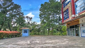 Ein Gebäude mit einem blauen Kiosk, einem befestigten Bereich und Bäumen im Hintergrund.