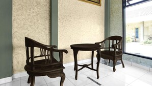 Dos sillas de madera y una mesa en una habitación con paredes estampadas y un ventanal grande.