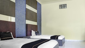 Habitación de hotel con dos camas, un ventanal grande y una pared lisa.