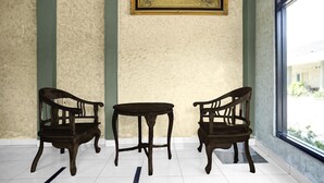 Una habitación con dos sillas de madera, una mesa pequeña, un cuadro en la pared y una ventana con vistas.