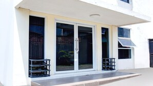 A building with a white exterior, large sliding glass doors, and a small outdoor seating area with metal chairs.