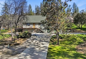 A two-story house with a front porch, a staircase leading to the second floor, and a driveway. - Peaceful chalet, Bass Lake and Yosemite, hot-tub (Oakhurst)