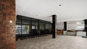 Un vestíbulo amplio con grandes ventanales, un revestimiento de madera y suelo de baldosas.