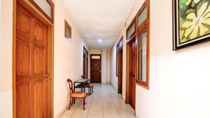 A hallway with wooden doors, a dining table with chairs, and a framed picture on the wall. - Family Luxury Suite W/Free WiFi and Parking (Semarang)