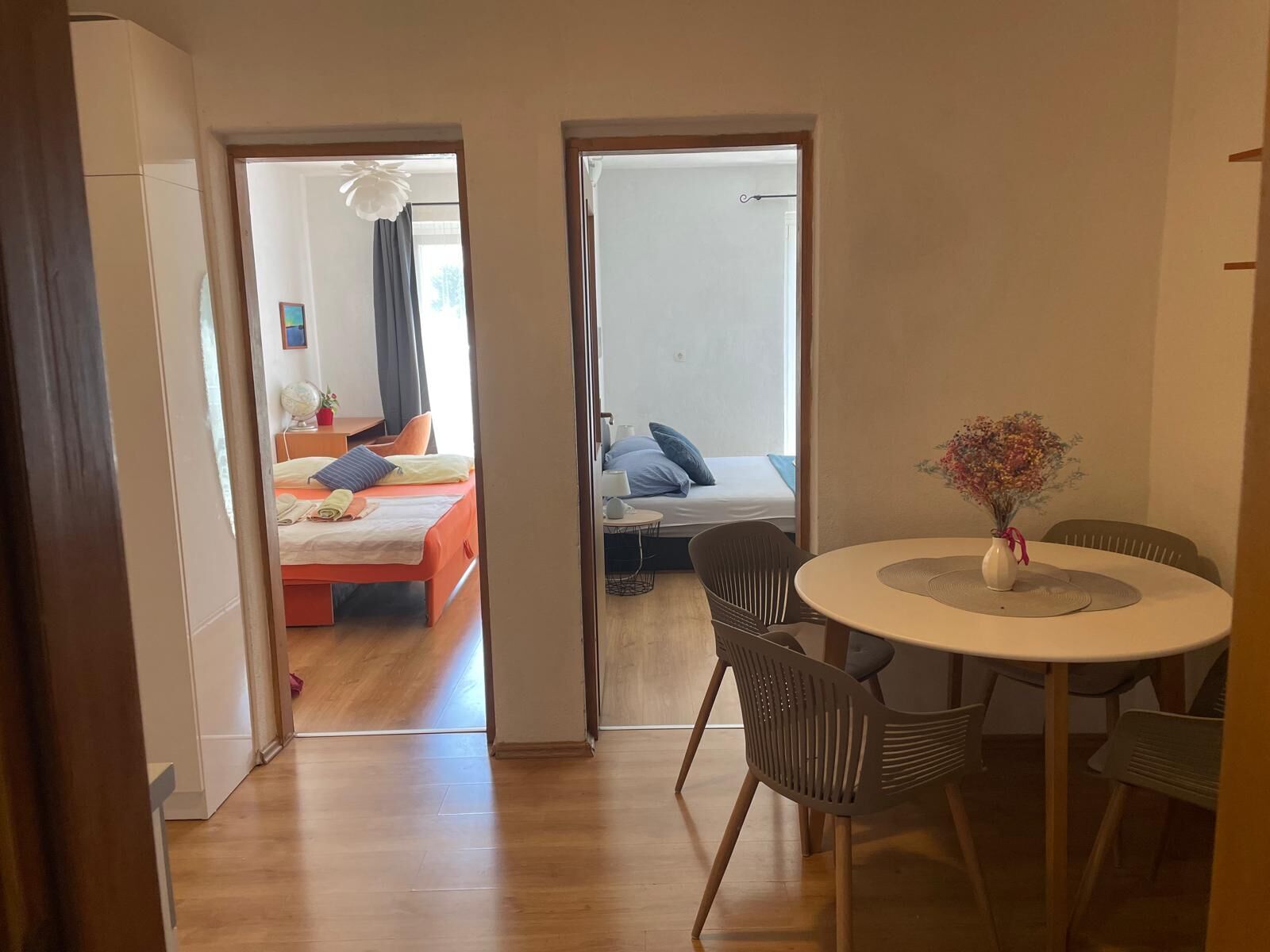 A hotel room with a bed, a desk, a chair, and a dining table with a vase of flowers.