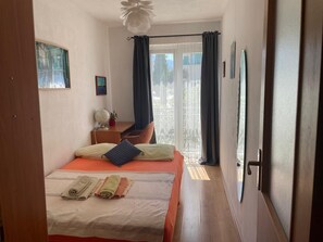 A bedroom with a bed, a desk, a globe, and a window with curtains.
