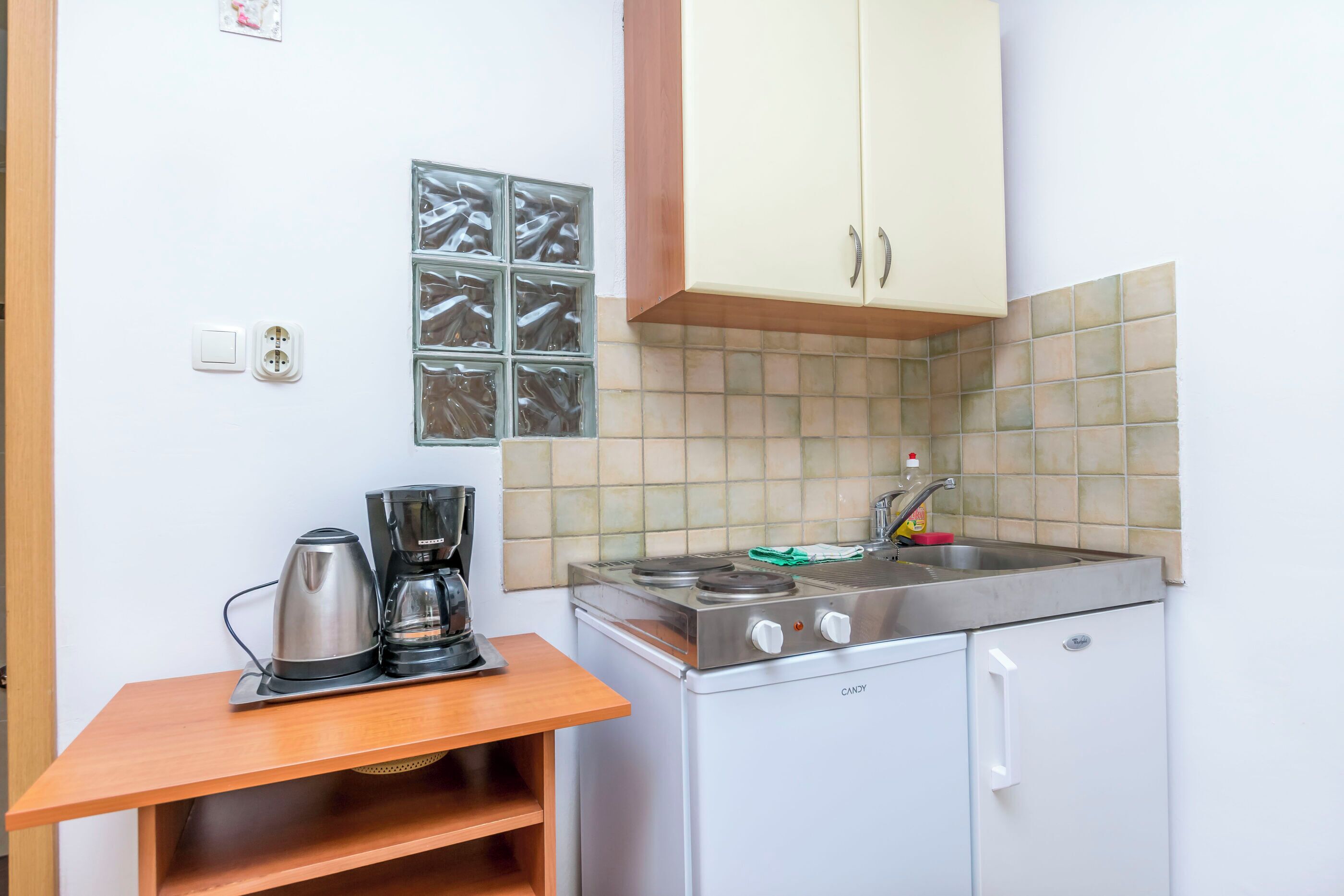 Une petite cuisine équipée d’une cuisinière, d’une machine à café et d’un petit évier.