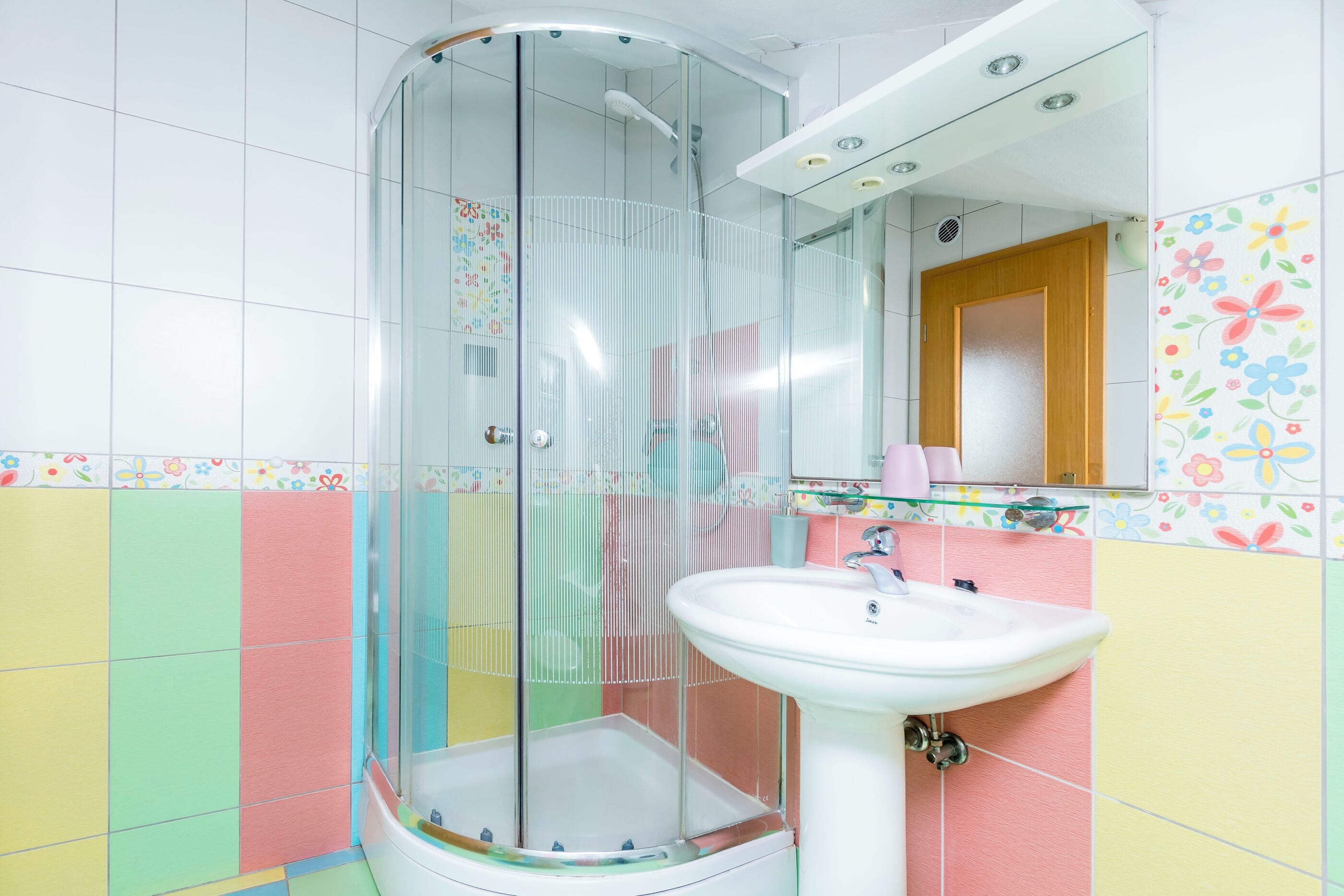 A bathroom with a glass-enclosed shower, a sink, and a mirror.