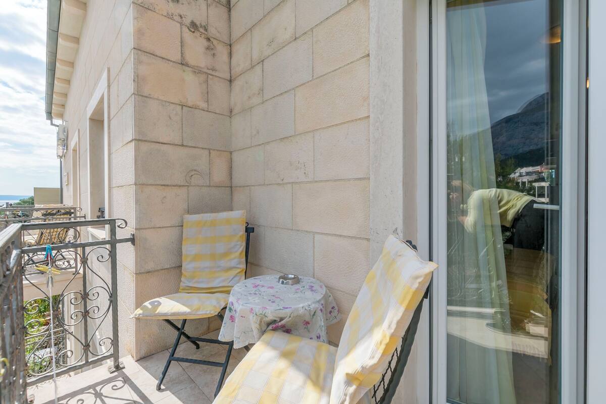 A balcony with two chairs, a small table, and a metal railing.