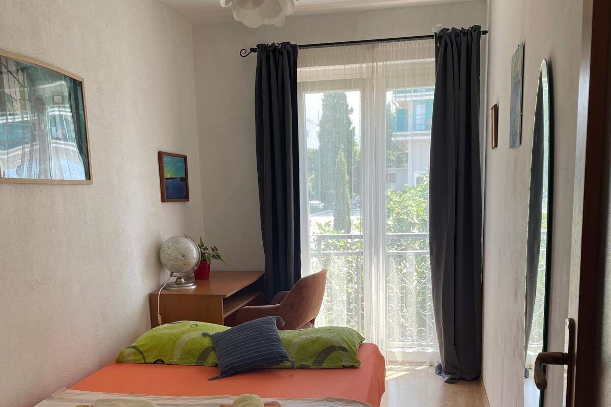 A hotel room with a bed, a desk, a chair, a globe, and a window with curtains.
