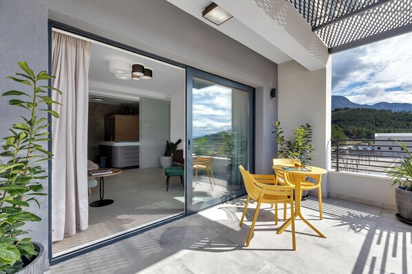 A balcony with a table and chairs, a sliding glass door, and a view of a mountainous landscape. - Apartment Luxury Wellness (Makarska)