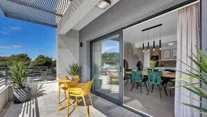 A modern balcony with a dining area, potted plants, and a view of the surrounding landscape. - Apartment Luxury Wellness (Makarska)